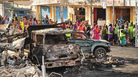 People gather near burned vehicles a day after a truck bomb exploded in the center of Mogadishu on October 15.