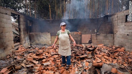 Inocencia Rodrigues, 64, walks among the debris of the burnt shed where she raised chickens and pigs in the village of Sao Joaninho in northern Portugal.