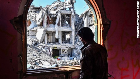 A member of the Syrian Democratic Forces (SDF),  forces, looks out from a building at the frontline in Raqqa on October 16.