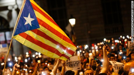 People hold candles and a Catalan flag during a demonstration in Barcelona against the arrest of two Catalan separatist leaders on October 17.