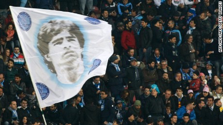fanoušci SSC Napoli mávají vlajkou zobrazující bývalého argentinského útočníka Diega Armanda Maradonu.