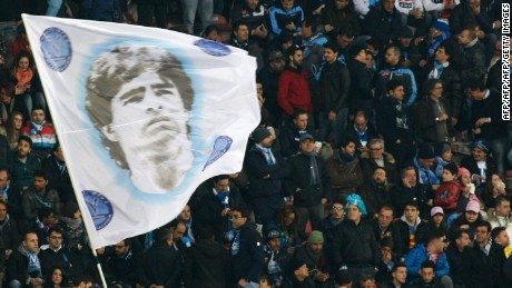 Fans of SSC Napoli wave a flag depicting former Napoli&#39;s Argentine forward Diego Armando Maradona during the Italian Serie A football match between SSC Napoli and AS Roma in San Paolo Stadium, in Naples, on March 09, 2014. AFP PHOTO/CARLO HERMANN        (Photo credit should read CARLO HERMANN/AFP/Getty Images)