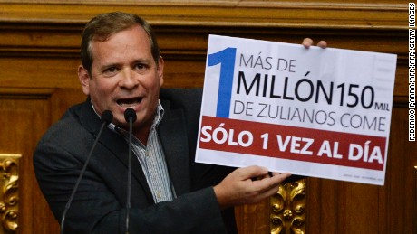 Opposition deputy Juan Pablo Guanipa (front) displays a placard that reads: "More than 1 million 150 thousand zulians eat just once a day"  in front of the President of the National Assembly Henry Ramos Allup, during a session in Caracas, on December 13, 2016. / AFP / FEDERICO PARRA        (Photo credit should read FEDERICO PARRA/AFP/Getty Images)