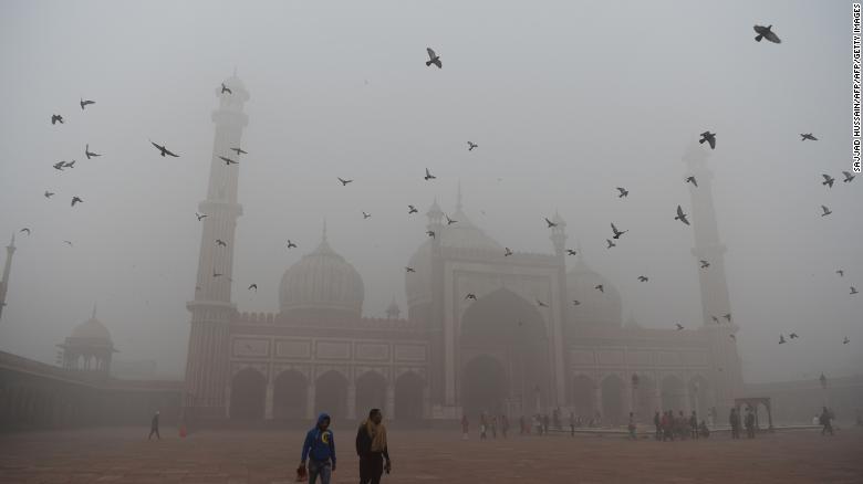Indian visitors walk through the courtyard of Jama Masjid amid heavy smog in the old quarters of New Delhi on November 8, 2017.