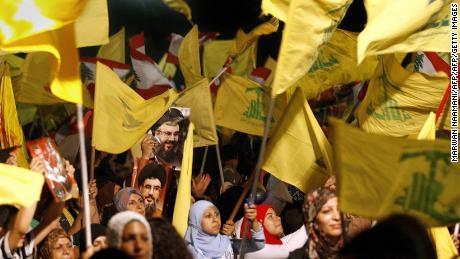 Images of Hezbollah chief Hassan Nasrallah are seen among scores of Hezbollah and Lebanese national flags being waved by Hezbollah supporters. 
