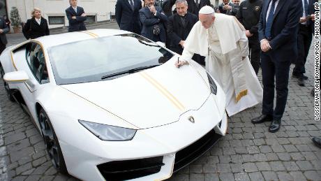 Pope Francis writes on the hood of a Lamborghini donated to him by the luxury sports car maker, at the Vatican.