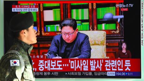 A South Korean soldier walks past a television showing North Korean leader Kim Jong Un approving the first test of the Hwasong-15. 