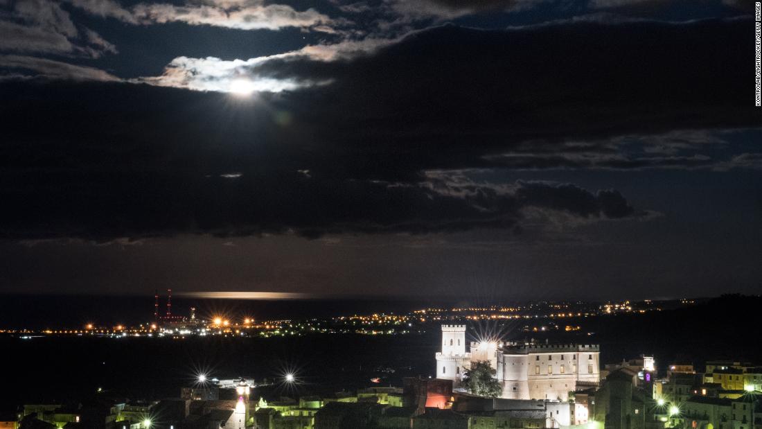 The year&#39;s only supermoon is bright behind the clouds above the Castle of Corigliano, in Calabria, southern Italy.