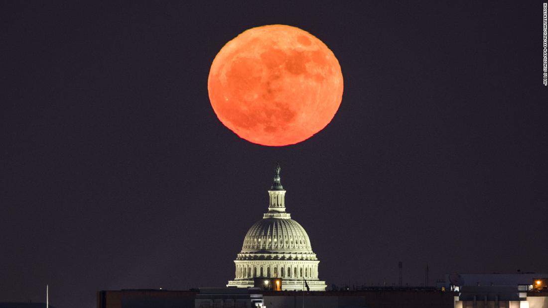 The moon rises behind the US Capitol in Washington, DC, viewed from Arlington, Virginia.