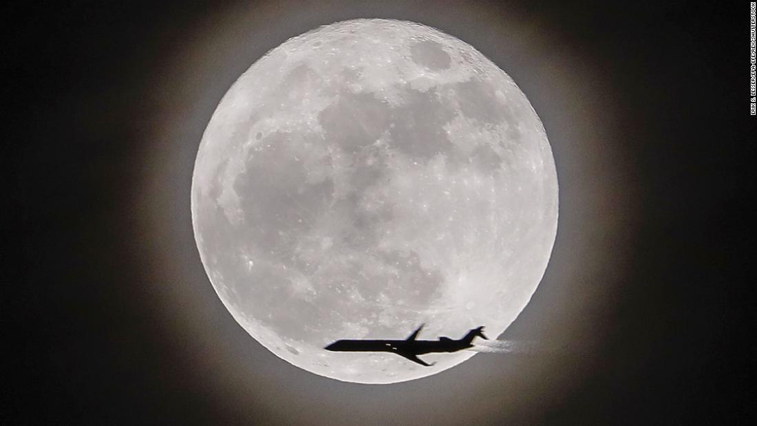 An airplane crosses in front of the moon, seen in Avondale Estates, Georgia.