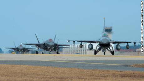 A US Air Force F-16 and four F-35A fighter jets taxi toward the end of the runway during exercise Vigilant Ace at Kunsan Air Base in South Korea.