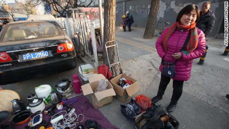 Zhao Guihua, an evicted migrant worker, sells her possessions on the street 50 meters from her old home. She said she and her husband are leaving Beijing because they can't afford a new home.