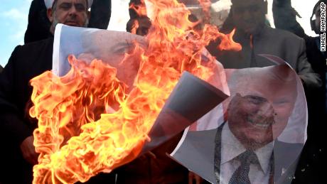 Palestinians burn posters of Israeli Prime Minister Benjamin Netanyahu and US President Donald Trump during a protest Thursday.