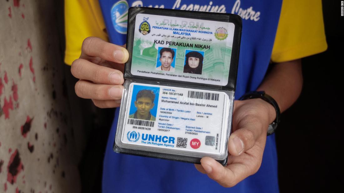 Mohammed Arafat Bashir Ahmed, 13, holds out his UNHCR refugee card. This record of their status is supposed to help protect refugees against forced return, arbitrary arrest and detention.