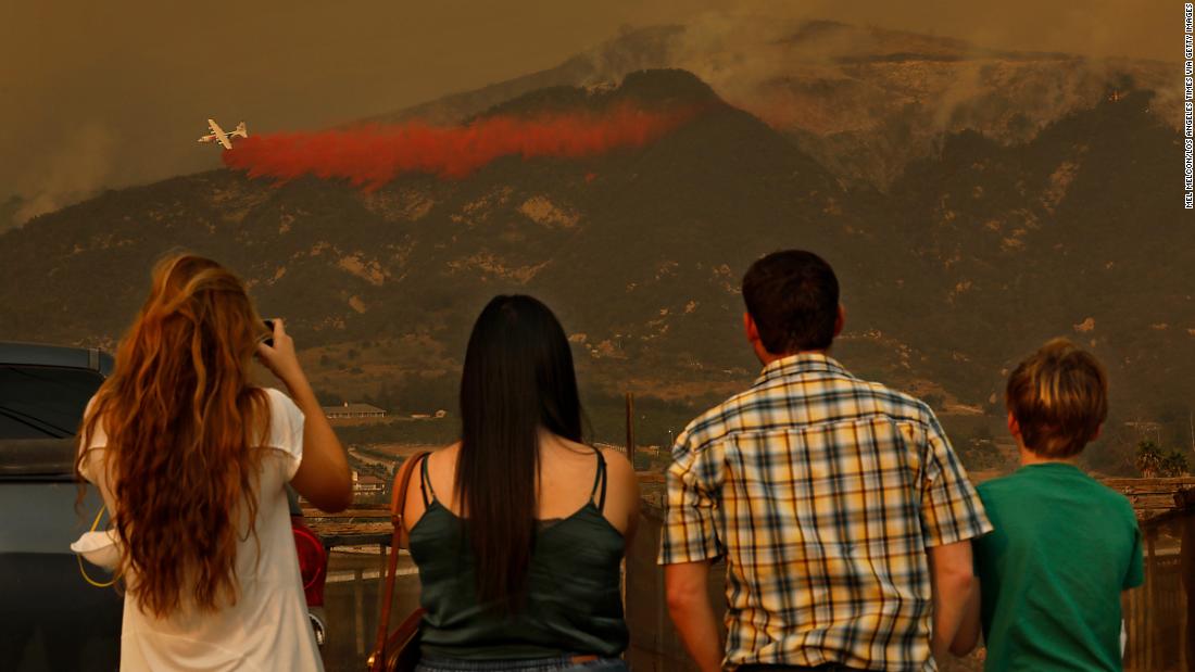 People watch as firefighters battle flames in Carpinteria, California, on Monday, December 11.