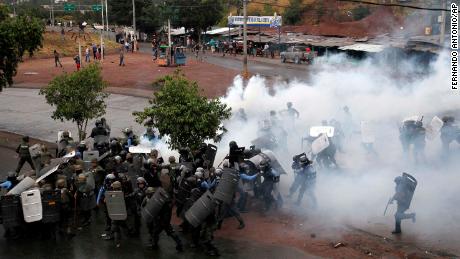 Police stand amid tear gas as they clash with supporters of opposition presidential candidate Salvador Nasralla in Tegucigalpa, Honduras, Monday, Dec. 18, 2017. 