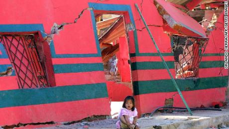 A girl sits in front of a building destroyed by the January 2001 earthquake in San Agustin, El Salvador.