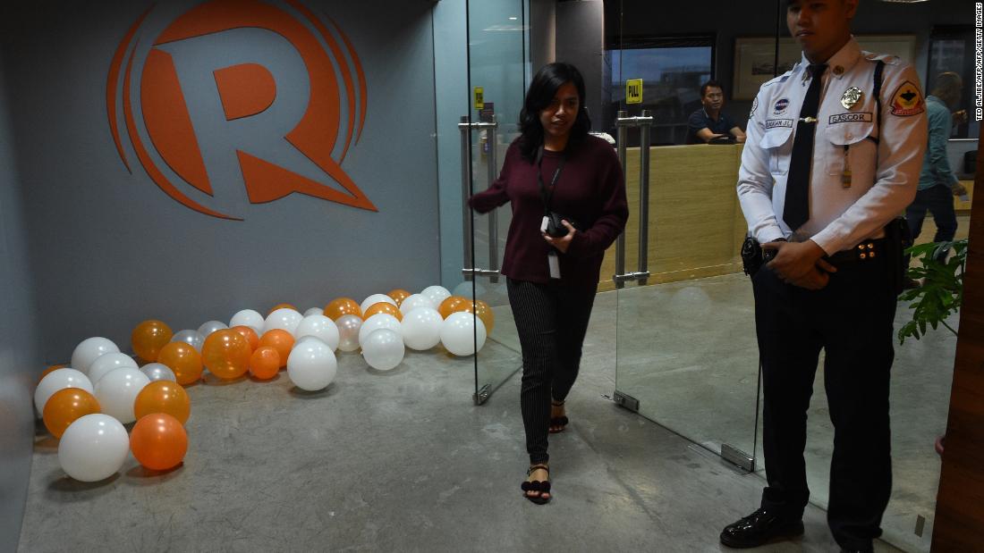 An employee of online portal Rappler heads out from their editorial office in Manila on January 15, 2018, while a private security guard stands. 