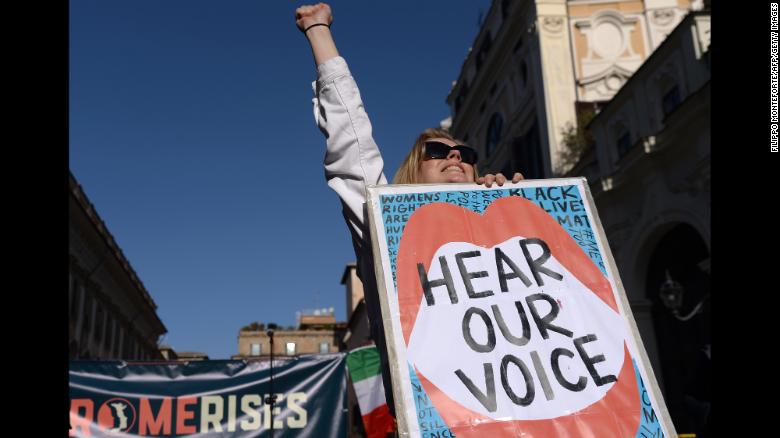 A woman lifts her fist while holding a banner during a Women&#39;s March demonstration in Rome.