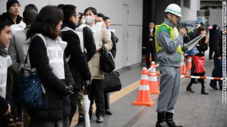 Participants stand outside a subway entrance as a worker with the Tokyo Metropolitan Government gives directions before the start of Monday's missile-attack drill in Tokyo.