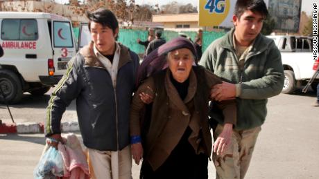 A wounded woman is assisted at the site of the attack Saturday in Kabul.