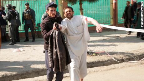 A wounded man is helped near the blast scene on Saturday.