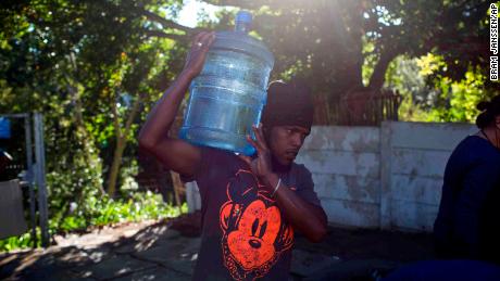 A man carries water at a source for natural spring water in Cape Town on Thursday.