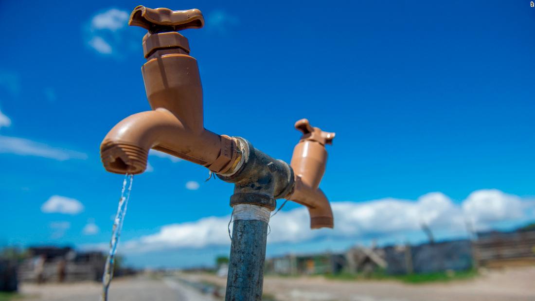 A communal tap runs as people collect water in an informal settlement near Cape Town on January 23.