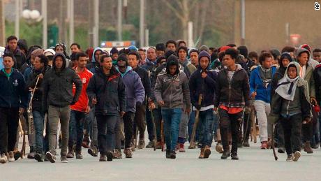Migrants carrying sticks march in the streets of Calais, northern France.