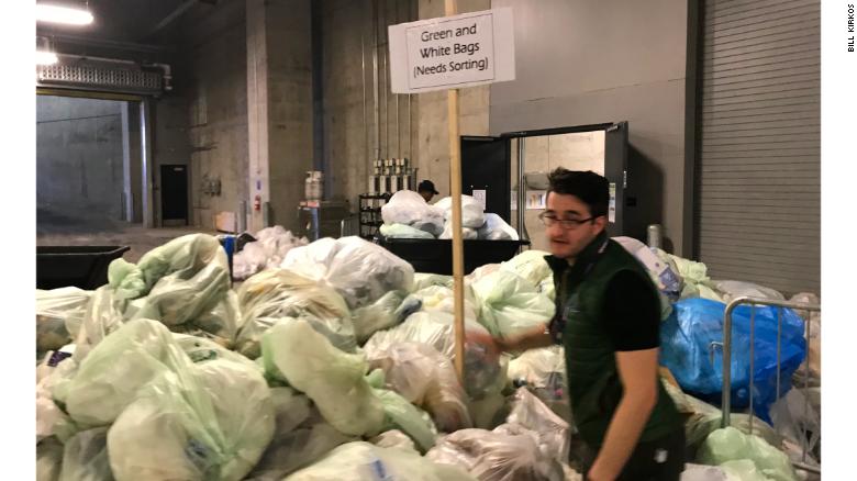 US Bank Stadium Sustainability Coordinator Bradley Vogel places a sign in the middle of a pile of trash bags for sorting on Monday. Green bags were for composting and white bags for waste.    