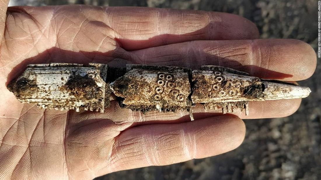 This is a fragment of another antler comb, which would have been similar to the one with runes. This one is decorated with ring-and-dot ornaments. The comb was burned, hence the white color.