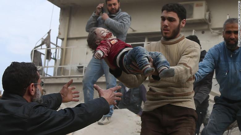 A man hands over a child to his father after being rescued from the ruins of a building in Eastern Ghouta on Tuesday.