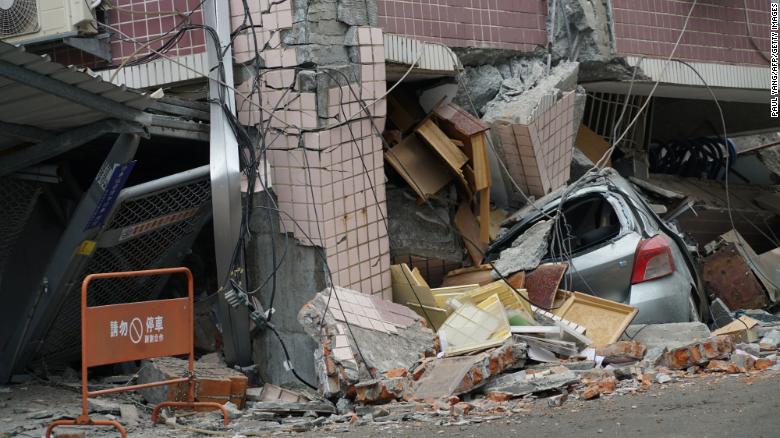 A car sits crushed under a building Wednesday after a 6.4 magnitude quake hit in Hualien.
