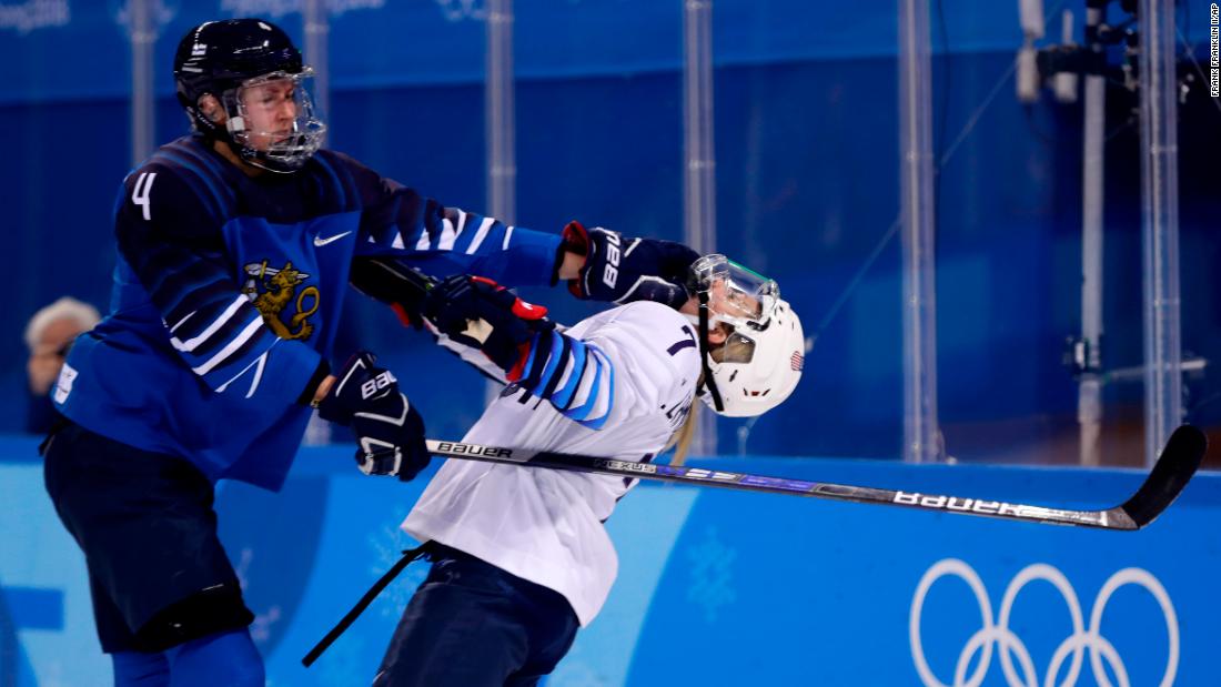 Monique Lamoureux-Morando of the United States, takes a punch from Rosa Lindstedt of Finland, during the preliminary round of the women&#39;s ice hockey.