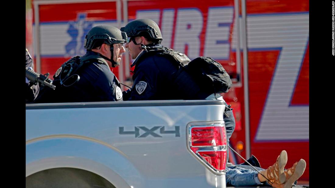 Police officers ride in the back of a pickup truck as they tend to a victim.