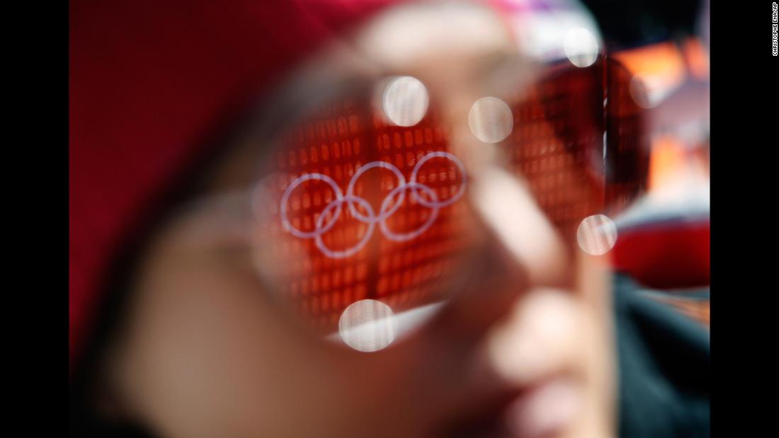 The Olympic rings are reflected in a spectator&#39;s sunglasses before the start of the women&#39;s super-G.