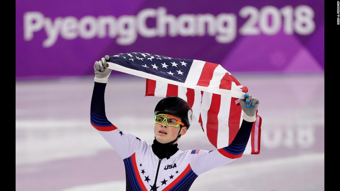 Short-track speedskater John-Henry Krueger celebrates with the American flag after winning silver in the 1,000 meters. Canada&#39;s Samuel Girard won the gold.