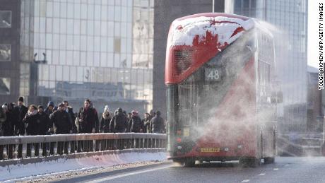 Snow blows off a bus as commuters cross London Bridge after snow hit London overnight.