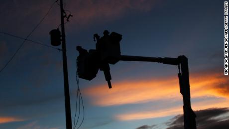 Puerto Rico Electric and Power Authority linemen works on a new utility pole placed in a residential area during sunset in Gurabo, last November.