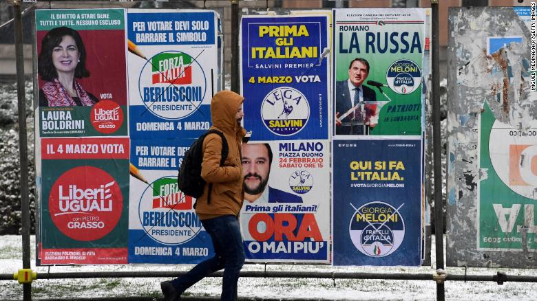 A pedestrian passes in front of election hoardings in Milan on March 1.