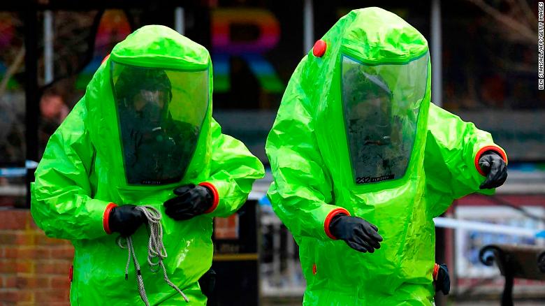 Members of the emergency services in green biohazard suits work to afix the tent over the bench where Sergei Skripal and his daughter Yuli were found.