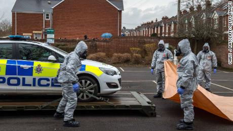 Military personnel wearing protective suits remove a police car from a parking lot as they investigate the poisoning.