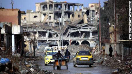 Syrians make their way along a destroyed street in Raqqa, on February 18, 2018. 