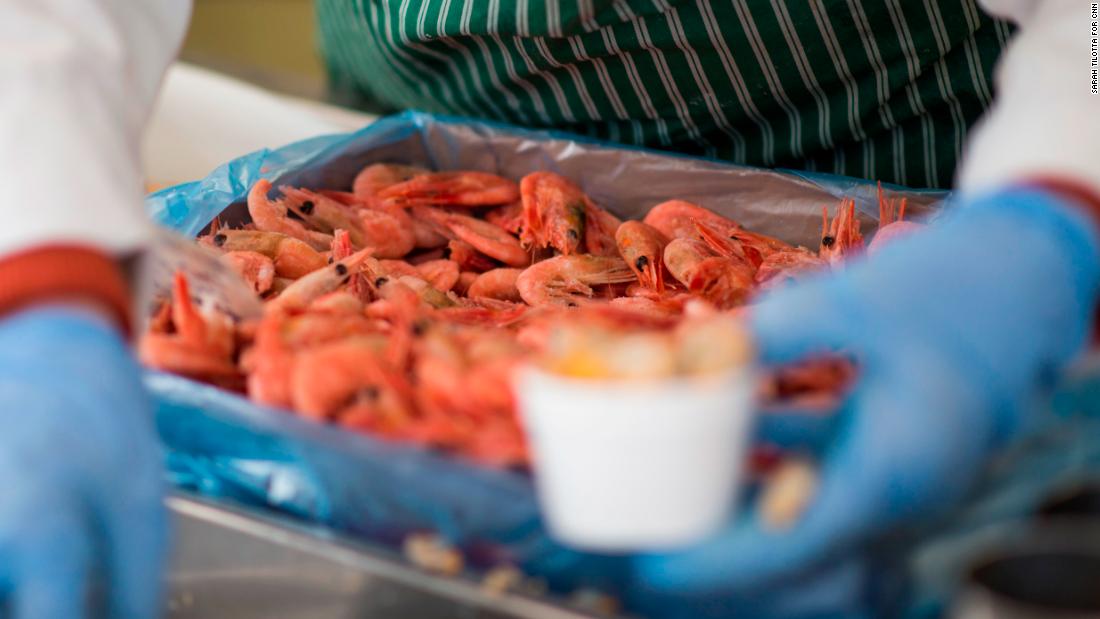 Fishmonger Dave Crosbie&#39;s wife serves customers at their stall in the market.