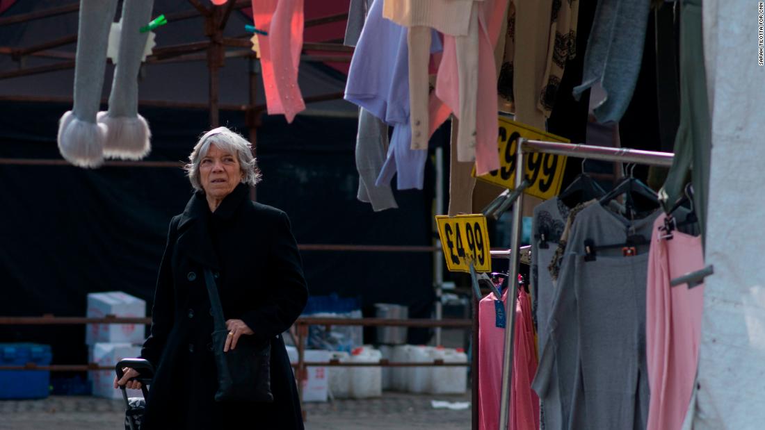 A woman browses through clothes at a market stall.