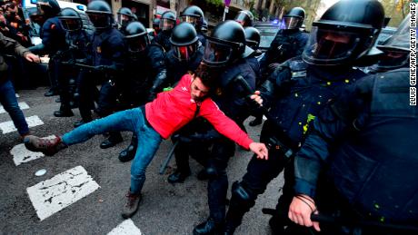 A protester is pulled by riot police blocking the road leading to the central government in Barcelona on March 25, 2018.