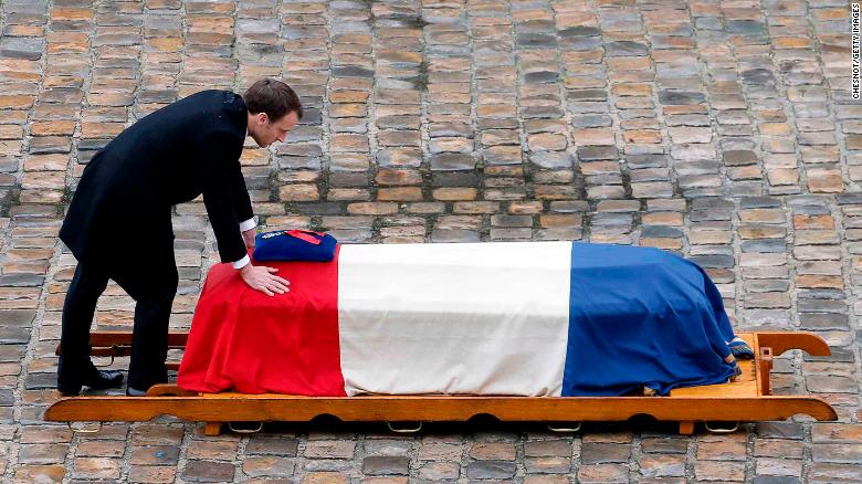 French President Emmanuel Macron touches the flag-draped coffin of Arnaud Beltrame.