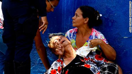 A woman is overcome by tear gas  used to disperse the relatives of prisoners waiting to hear news about their family members.