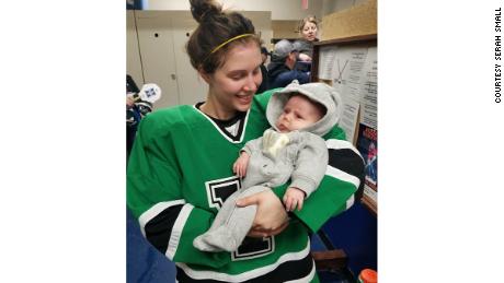 Serah Small holds her 8-week old baby, Ellie, while wearing her hockey uniform. 