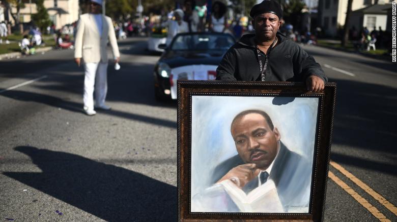 Artist Al Hornsby marches with his painting of  Martin Luther King Jr. in 2015. There are many ways to honor King's memory.